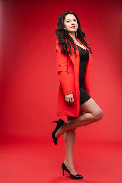 Brune confiante en robe noire et veste rouge posant
 - Photo, image