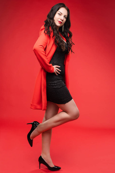 黒いドレスと赤いジャケットのポーズで自信を持ったブルネット - 写真・画像