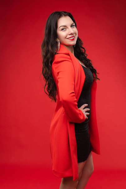 Confident brunette in black dress and red jacket posing - Φωτογραφία, εικόνα