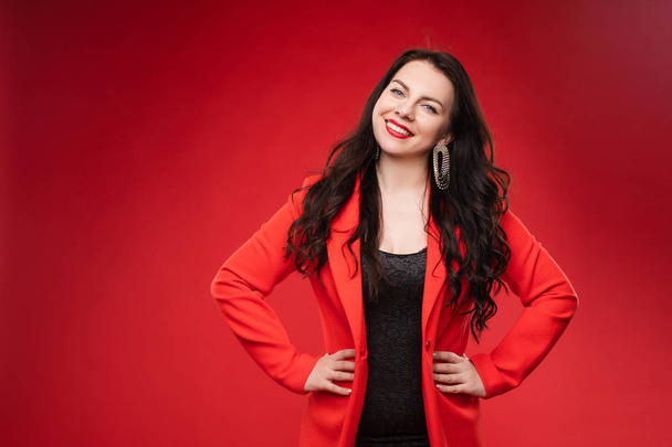Confident brunette in black dress and red jacket posing - Foto, Imagen