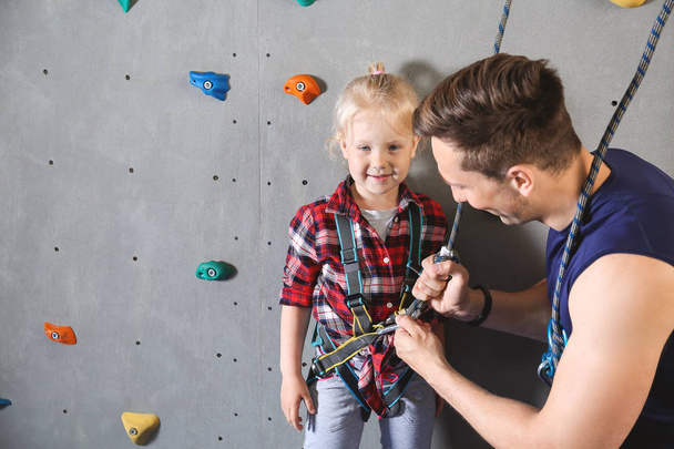 Instructor teaching little girl to put on climbing gear in gym - Foto, immagini