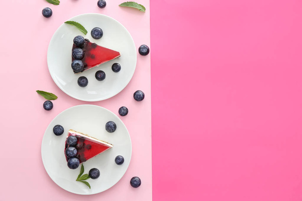 Pieces of tasty blueberry cheesecake on color background - Zdjęcie, obraz