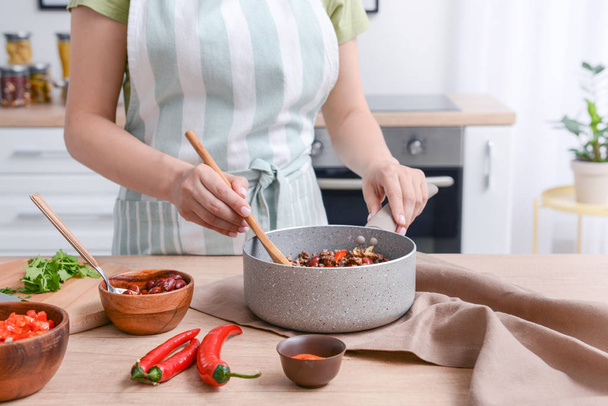 Nő főzés hagyományos chili con Carne a konyhában - Fotó, kép