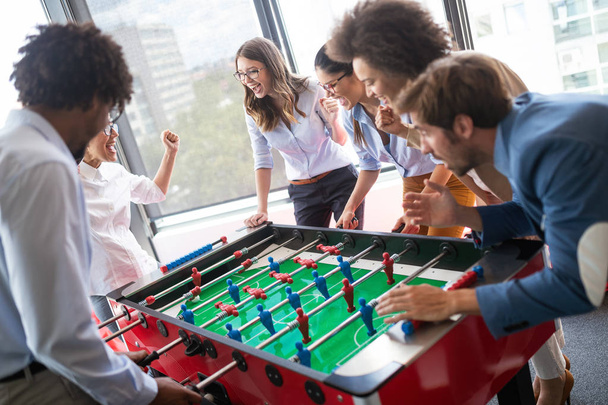 Colleagues playing table football in the break in office - Foto, imagen