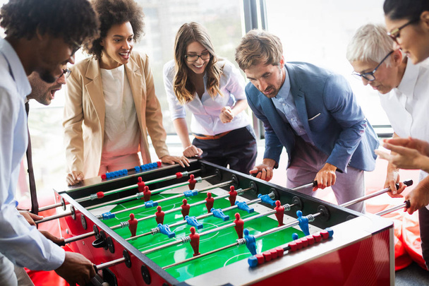 Employees playing table soccer indoor game in the office during break time to relieve stress from work - 写真・画像
