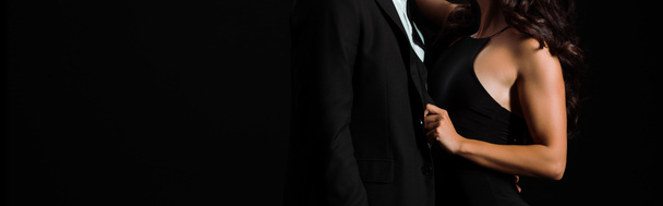 plano panorámico de mujer tocando traje de hombre aislado en negro
  - Foto, imagen