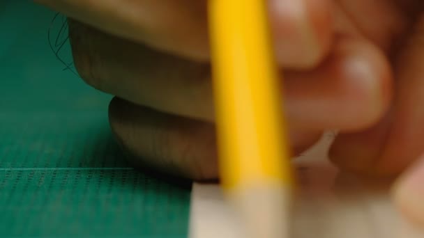 Primo piano delle mani maschili dell'architetto che disegnano una linea su cartone bianco con righello e matita gialla. processo di fabbricazione del modello
. - Filmati, video