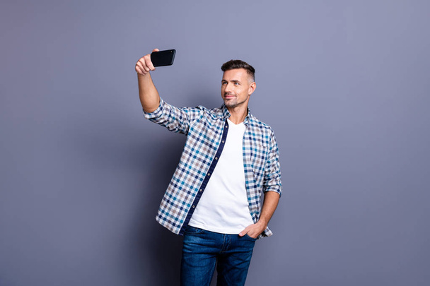Portrait of his he nice attractive content cheerful cheery bearded grey-haired guy wearing checked shirt holding in hand cell making selfie isolated over blue violet pastel background - Foto, immagini