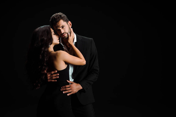 young attractive woman hugging bearded man isolated on black  - Fotoğraf, Görsel