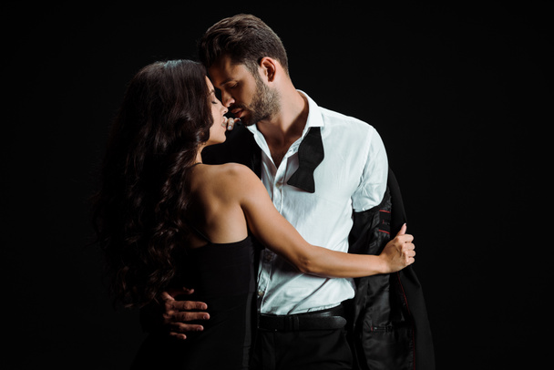 young beautiful woman undressing bearded man isolated on black  - Photo, Image