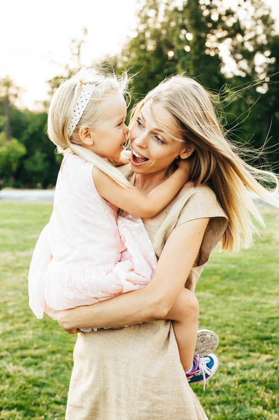 Young mother lifting and holding her happy daughter in her arms both smiling - Photo, image