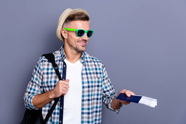 Close up photo handsome he him his guy arm hand giving security terminal passport tickets go abroad foreign country airline hat bag wear sun specs casual plaid checkered shirt isolated grey background - Фото, изображение