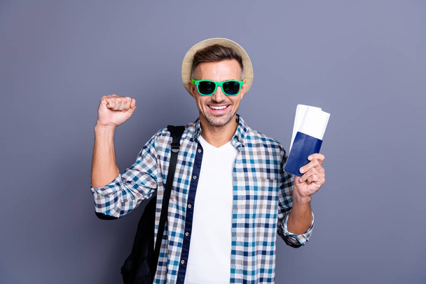 Close up photo handsome he him his guy arm hand passport tickets won lottery go free abroad foreign country funny hat bag wear sun specs casual plaid checkered shirt isolated grey background - Photo, image