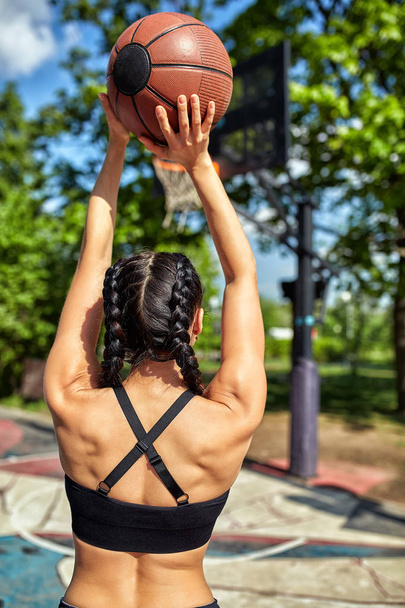 Beautiful, sporty latin girl with a basketball is preparing to make a ring. Achieving the goal, hitting the goal, sports motivation, healthy lifestyle, copies of the space, advertising banner. - Fotó, kép