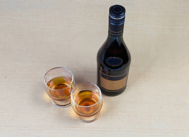 Deux verres et une bouteille de brandy sur une surface textile
 - Photo, image