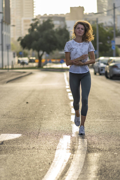 junge Sportlerin macht Übungen auf dem Rasen in einer Stadt  - Foto, Bild