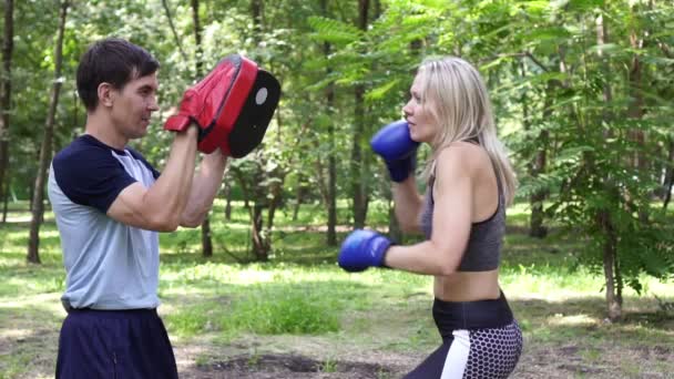 Young beautiful woman is practicing boxing. Woman boxing with an instructor. - Footage, Video