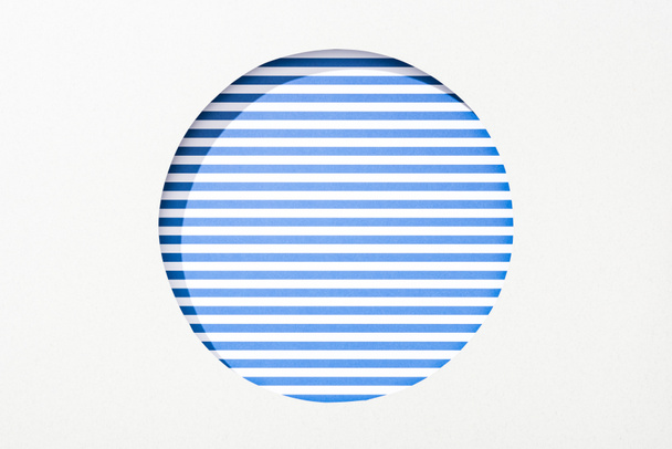 cut out round hole in white paper on blue and white striped background - Foto, Bild
