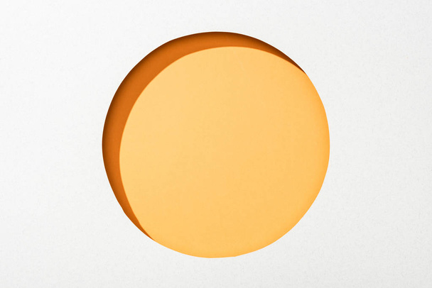 cut out round hole in white paper on orange colorful background - Fotoğraf, Görsel
