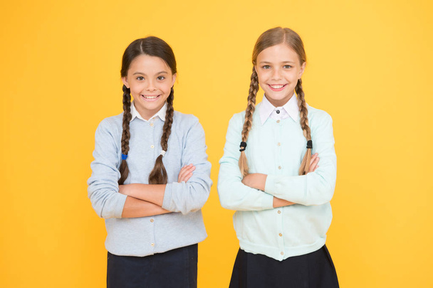 Studying together is fun. smart little girls on yellow background. knowledge day. happy childhood. kid fashion. Friendship and sisterhood. education concept. back to school. girls in school uniform - Photo, Image