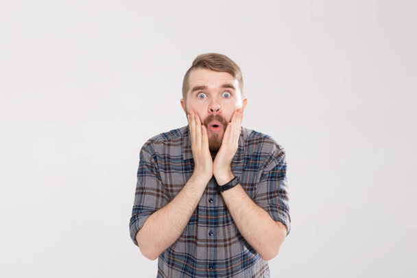 Stylish young hipster man with a mustache and beard joyfully opens his mouth on a white background. Concept of surprise and shock. - Photo, Image