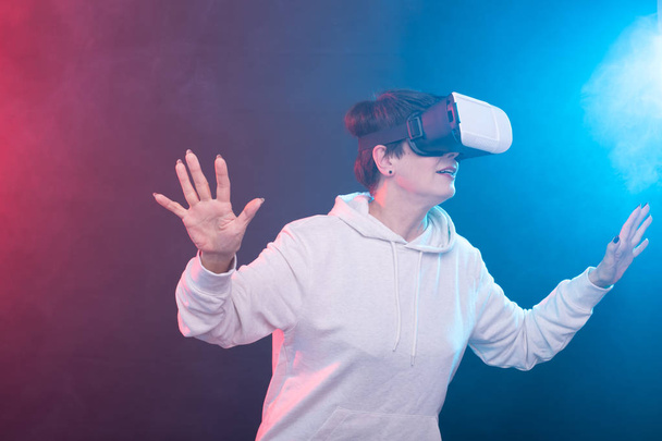 Középkorú boldog fiatal nő segítségével a virtuális valóság headset piros-kék háttér. - Fotó, kép