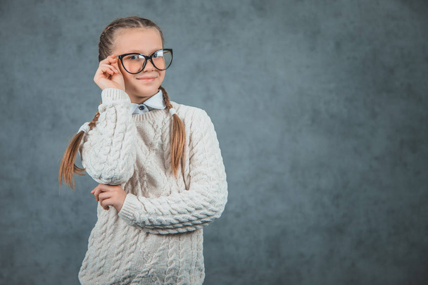 Close up foto di bella sorridente giovane studentessa in occhiali con un comodo maglione è isolato su sfondo grigio
 - Foto, immagini