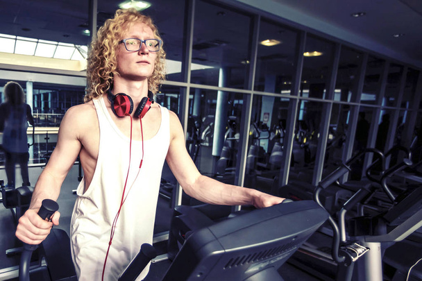 Thin curly blond  guy in glasses on the speedwalk. - Photo, Image
