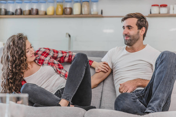 Beautiful girl and a young man sitting on the couch and watch TV. People relax on the couch.Young man in glasses and blue shirt.Young woman with glasses. - Фото, изображение