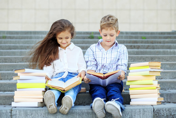 Two schoolchildren read books. The concept is back to school, education, reading, friendship and family - Foto, imagen