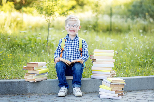 Ένα μικρό παιδί με γυαλιά και βιβλία. Πίσω στο σχολείο. Η έννοια της μάθησης, του σχολείου, του μυαλού, του τρόπου ζωής - Φωτογραφία, εικόνα