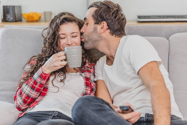 True love. Cheerful romantic couple sitting on the couch in a cozy room and smiling. - Photo, Image