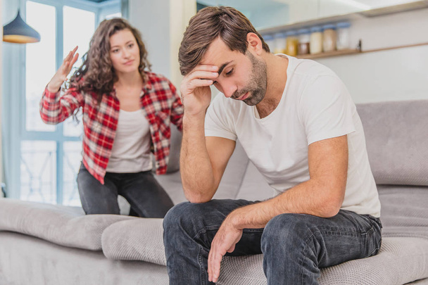 Couple argue. The wife shouted to her desperate husband, sitting on the couch in the living room at home. A man does not look at his wife. - Photo, image