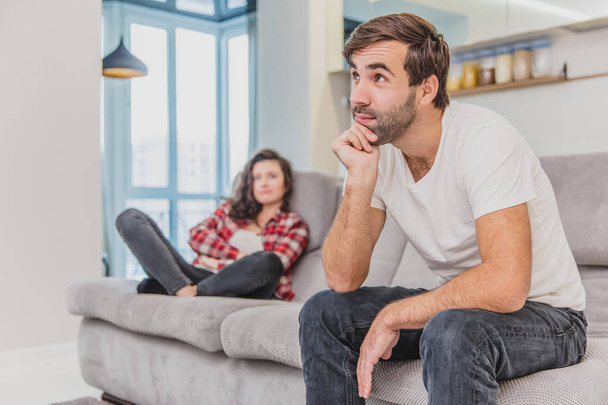 Couple argue. The wife shouted to her desperate husband, sitting on the couch in the living room at home. A man does not look at his wife. - Foto, Bild