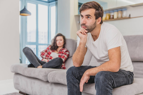 Couple argue. The wife shouted to her desperate husband, sitting on the couch in the living room at home. A man does not look at his wife. - Foto, afbeelding