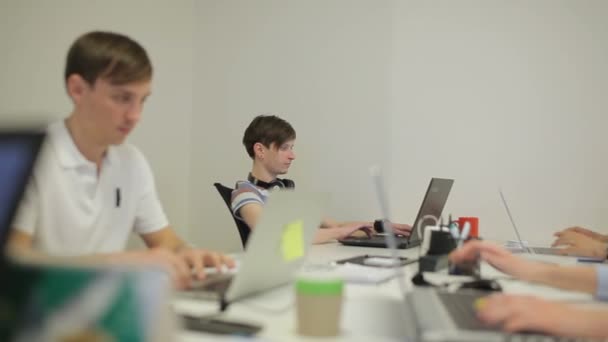 Due giovani uomini che lavorano in ufficio al laptop. In primo piano una donna sta digitando sul computer portatile
. - Filmati, video