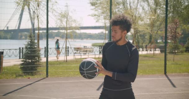 Closeup side view portrait of young handsome african american male basketball player throwing a ball into a hoop outdoors - Filmagem, Vídeo