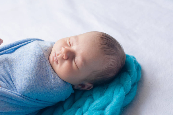 Cute little baby in a blue blanket on the bed at home - Foto, Imagen