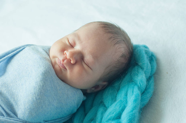 Cute little baby in a blue blanket on the bed at home - Foto, Imagen