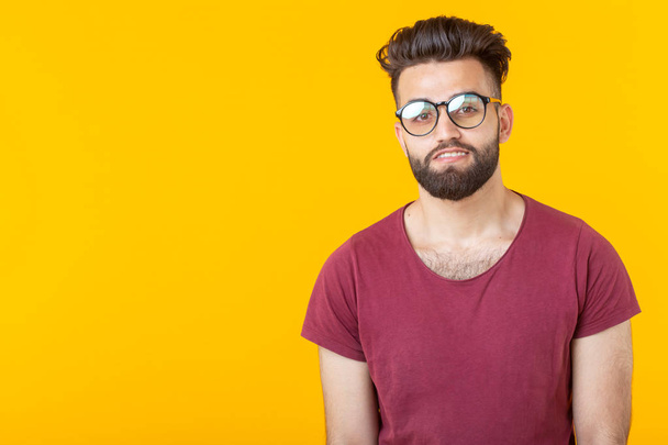 Retrato de un guapo estudiante joven árabe en camisa borgoña posando sobre un fondo amarillo con espacio para copiar. Concepto de oportunidad para los jóvenes
 - Foto, imagen