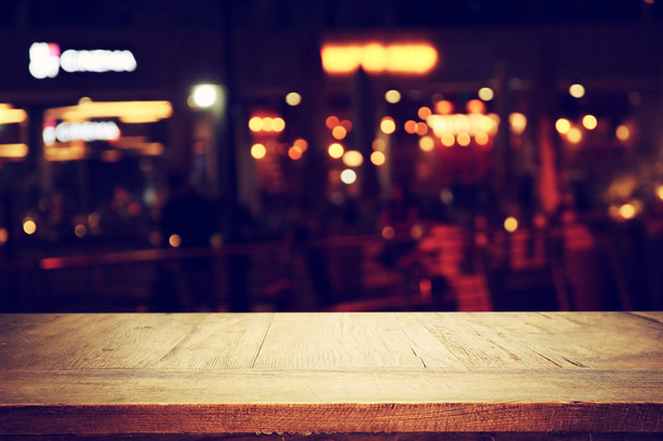 Bild eines Holztisches vor abstrakten verschwommenen Restaurant-Lichtern Hintergrund - Foto, Bild