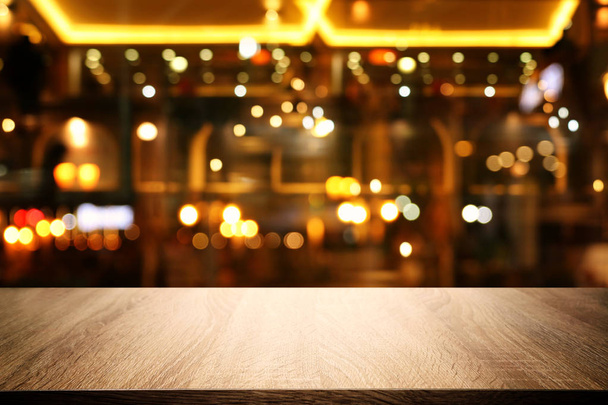 Image of wooden table in front of abstract blurred restaurant lights background - Fotoğraf, Görsel