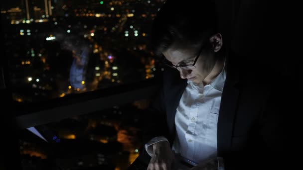 Nezávislý mladý muž pracuje na svém počítači u okna doma v noci.. - Záběry, video