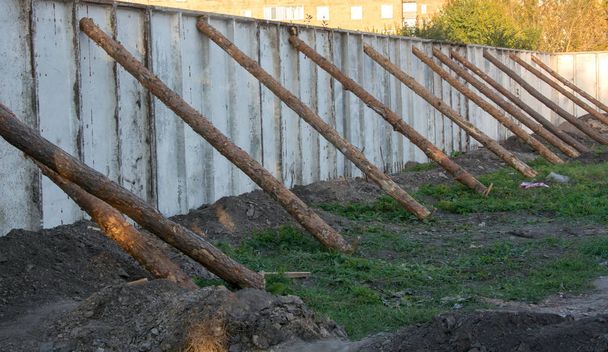 Бетонный забор, поддерживаемый стволами деревьев
 - Фото, изображение