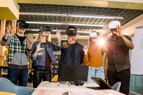 Teamwork trying virtual reality glasses for work in creative office. Young people using new technology at startup. Trends , social and business concept - Foto, imagen
