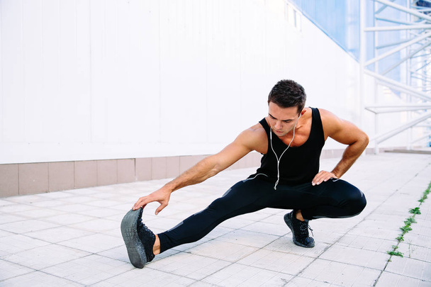 Sportive man stretching his body during workout outside - Zdjęcie, obraz