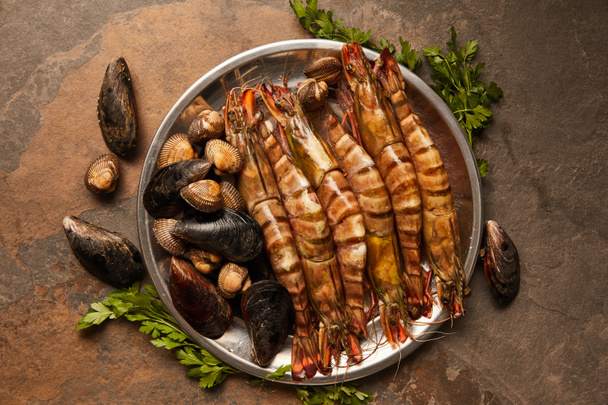 top view of shellfish, cockles and mussels with greenery in bowl on textured surface  - Photo, Image