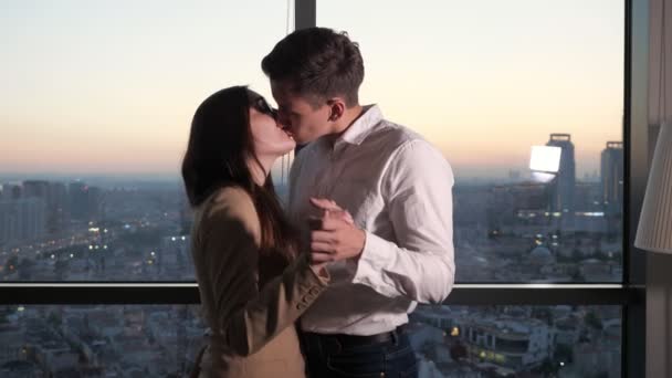Para, mężczyzna i kobieta tańczą i całują się w pobliżu panoramicznego okna z widokiem na miasto. - Materiał filmowy, wideo