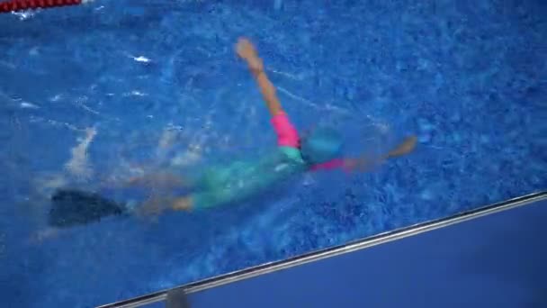 ゴーグルの水着キャップとフリッパーの子供の女の子は、プールで水泳を訓練しています. - 映像、動画