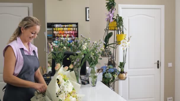 Kobieta Kwiaciarnia sellor daje bukiet kwiatów do człowieka klienta w Kwiaciarstwo sklep. - Materiał filmowy, wideo